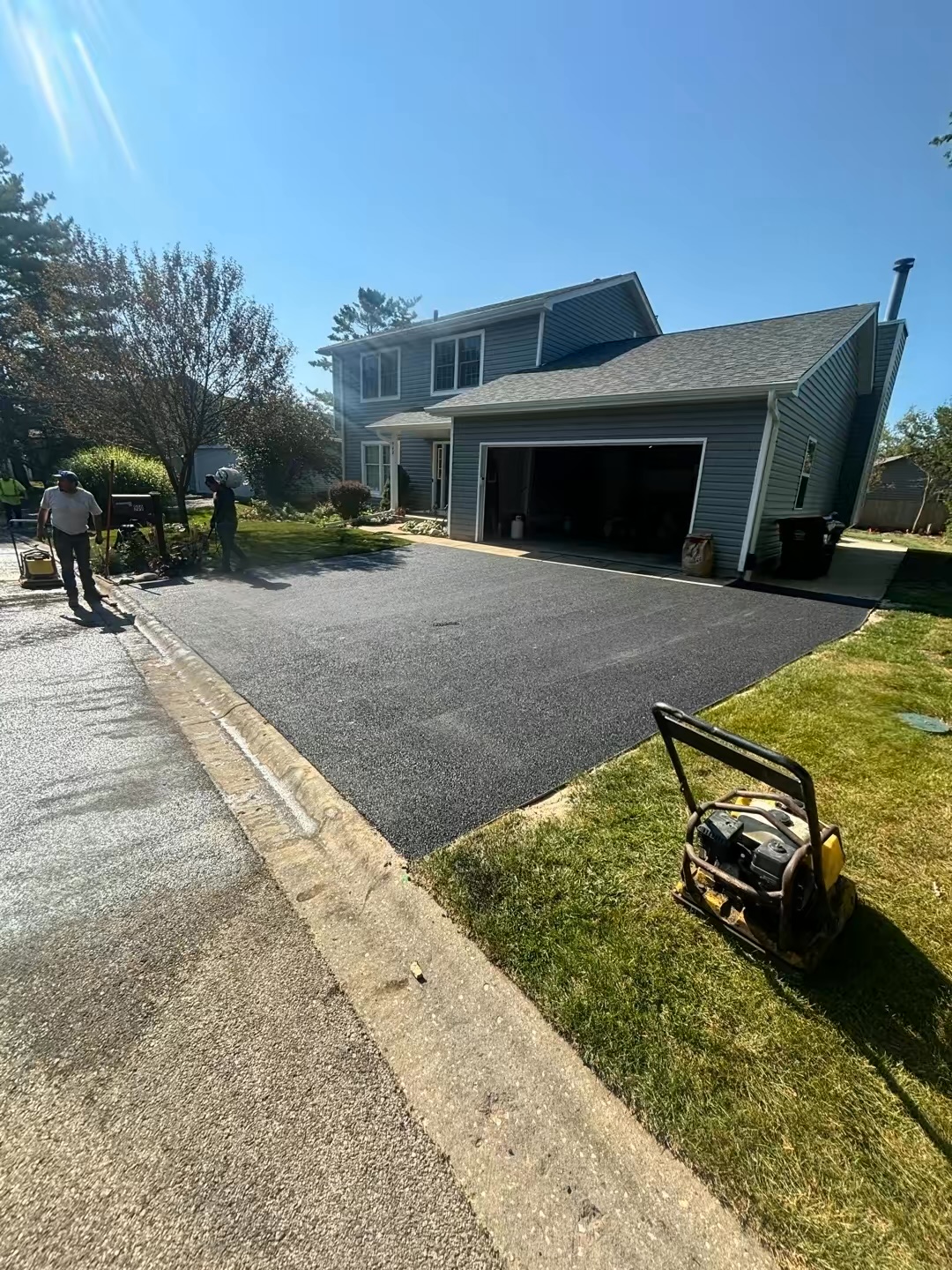 Asphalt driveway compaction with plate compactor by RCC crew in Northern Illinois