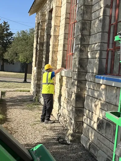 RCC crew member inspecting and detailing window frame on stone building facade