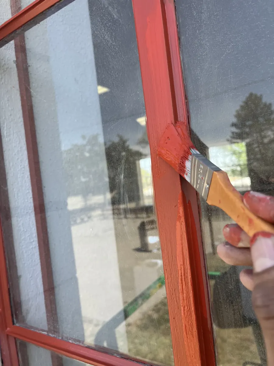 Close-up of RCC crew member hand-painting window trim during restoration